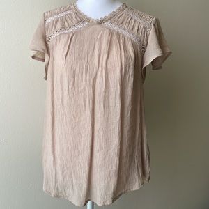 Nude color blouse with ruffles on the sleeves.